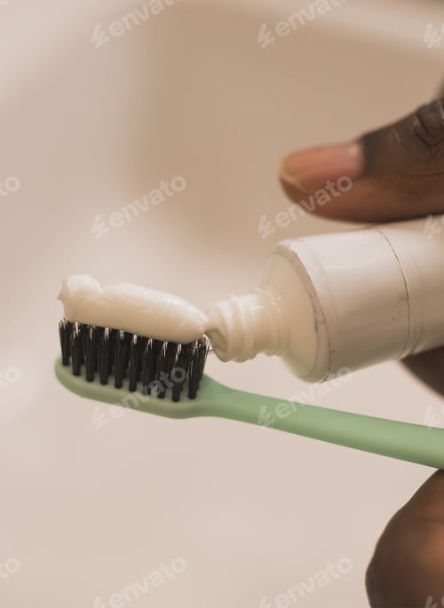 Preview: African american male hand holding toothbrush with toothpaste applied on it in bathroom. Close up of