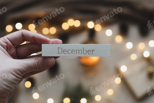 Preview: Word December on calendar by background with spruce branches and a glowing garland. Christmas