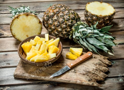 Preview: Sliced pineapple in a bowl on a cutting Board with a knife and a whole pineapple.