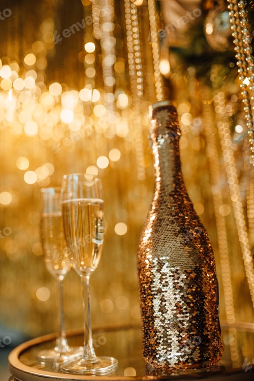 Preview: Champagne glasses and bottle against luxe glow golden rain decoration expensive holidays party