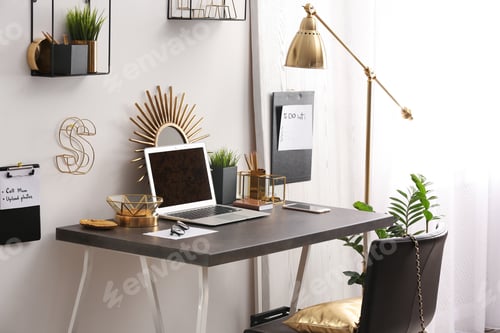 Preview: Modern workplace with laptop and golden decor on desk near wall. Stylish interior design