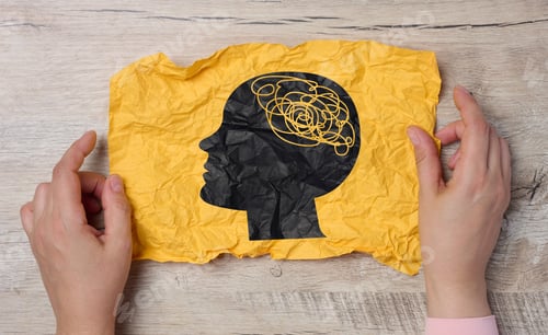 Preview: A female hand holds a crumpled paper with a black silhouette of a person's head