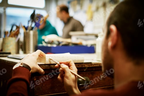 Preview: A man working on the bound pages of a book with a hand tool, to apply glue.