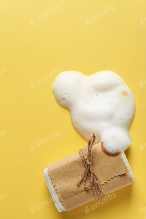 Preview: Craft soap bar and foam on color background, flat lay. Space for text