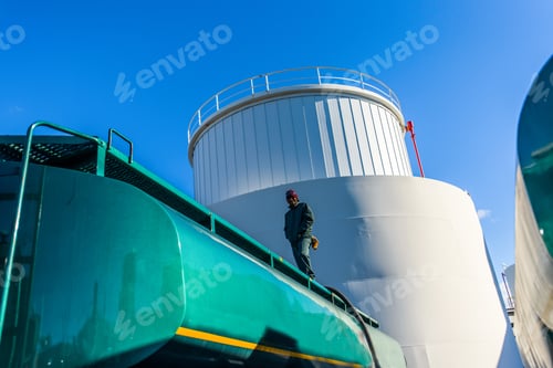 Preview: Low angle view of worker on top of biofuel oil tanker at biofuel plant