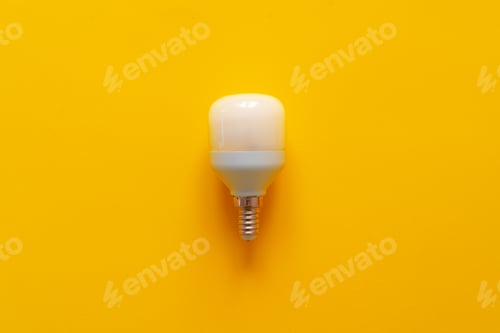 Preview: Light bulb on yellow paper background top view