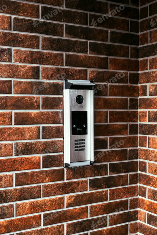 Preview: Modern intercom device at residential building entrance door with camera and dial keypad lock