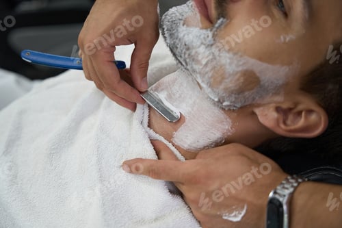 Preview: Laid-back gentleman with face covered in foam getting a shave