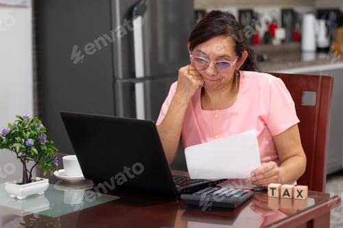 Preview: Woman Calculates Taxes with Laptop at Home
