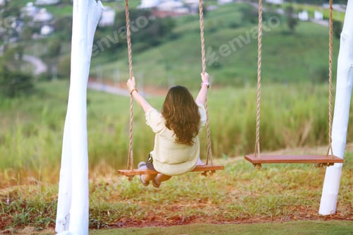 Preview: Candid of happy woman sitting in rope swing closeup outdoor nature garden blur background