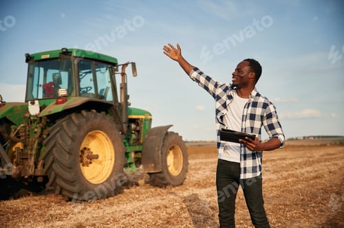 Preview: Standing, holding tablet. Beautiful African American man is in the agricultural field