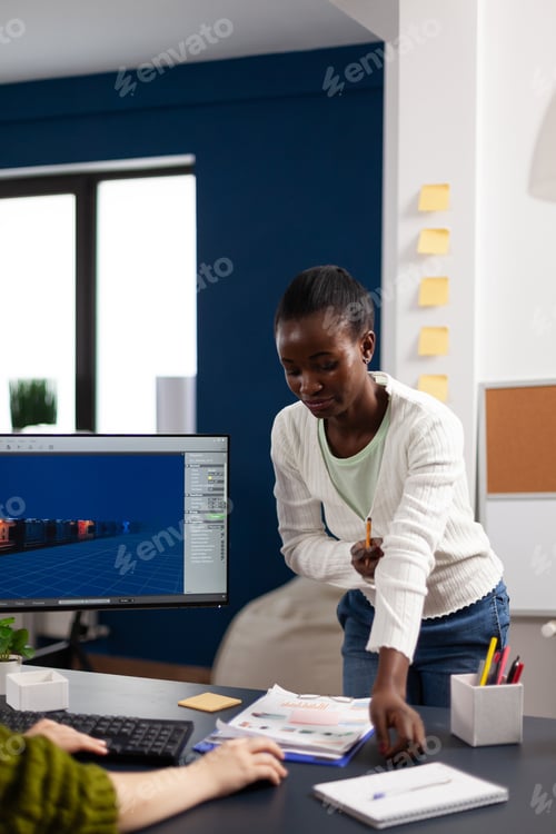 Preview: Multiethnic women designer looking at computer with dual displays