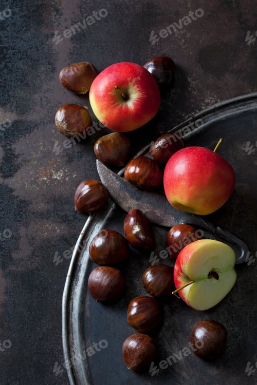 Preview: Sliced and whole apples, sweet chestnuts and an old knife on rusty background