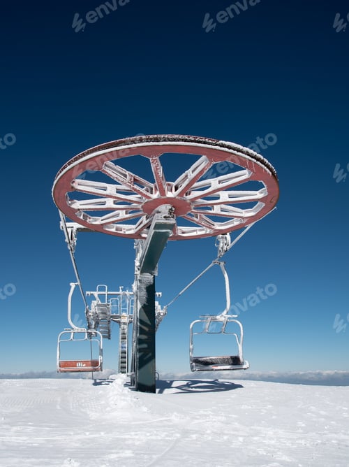 Preview: Frozen Ski lift on a snowy mountain against blue sky.