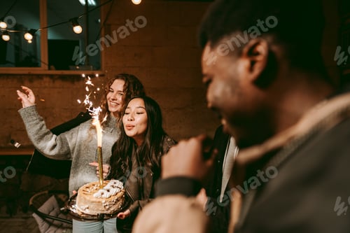Preview: Friends celebrate with a birthday cake and sparklers at an evening gathering outdoors