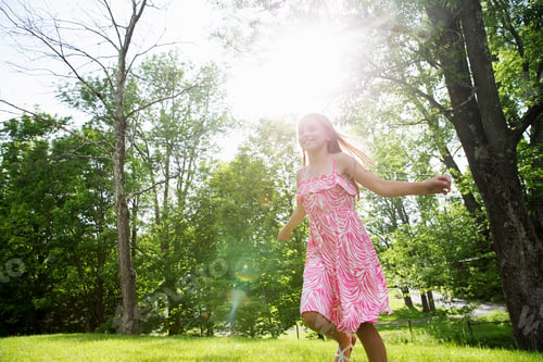 Preview: A young girl running across the grass under the trees in a farmhouse garden.