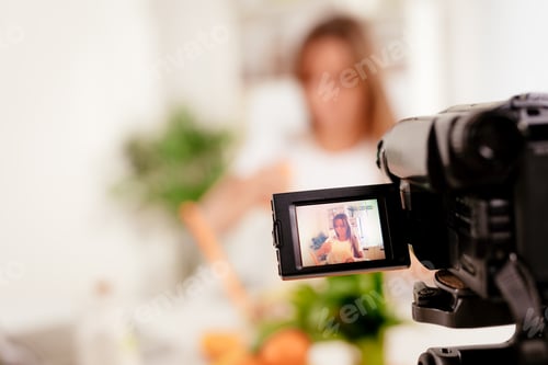 Preview: Woman recording video in kitchen with a camera