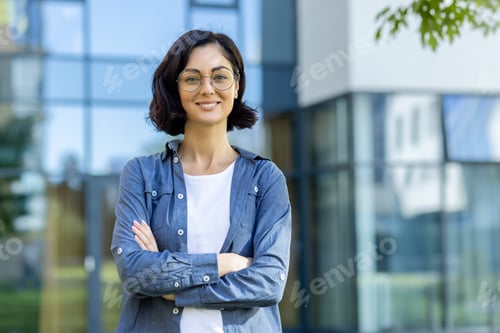 Preview: Portrait of a young beautiful woman in casual clothes standing outside an office center and campus