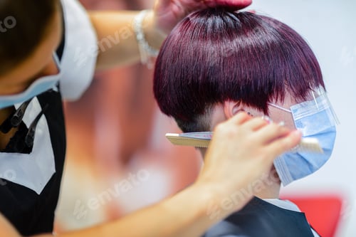 Preview: Closeup shot of a female getting her hair done wearing a face mask - concept of the new normal