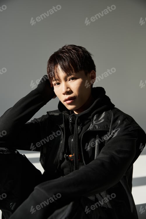 Preview: Stylish young man poses thoughtfully against a minimalist background in urban setting