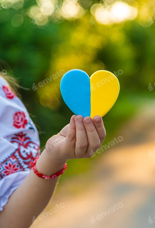 Preview: A child holds a heart of the Ukrainian flag. Selective focus.