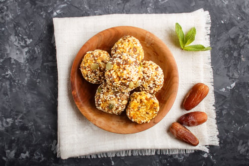 Preview: Energy ball cakes with dried apricots, sesame, linen, walnuts and dates with green mint leaves