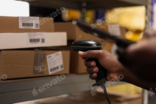 Preview: Black staff member using a barcode scanner to process shipping labels on boxes
