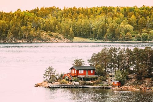Preview: Sweden. Many Beautiful Red Swedish Wooden Log Cabin House On Rocky Island Coast In Summer. Lake Or