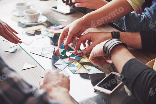 Preview: Group of creative friends sitting at wooden table. People having fun while playing board game