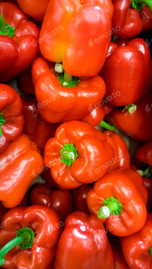 Preview: Closeup image of lots of red an orange bell peppers lying on counter in store