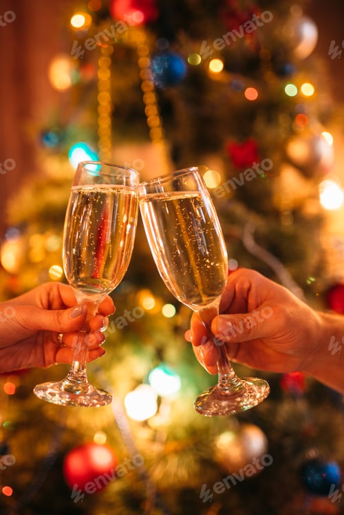 Preview: Two hands clink glasses with champagne, christmas