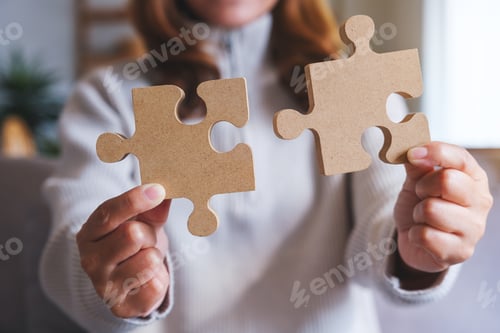 Preview: Closeup image of a woman holding and putting a piece of wooden jigsaw puzzle together