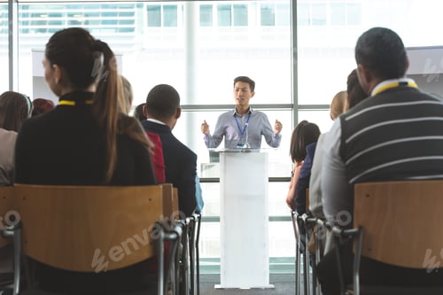 Preview: Young male businessman speaking in front of business professionals in business seminar in office