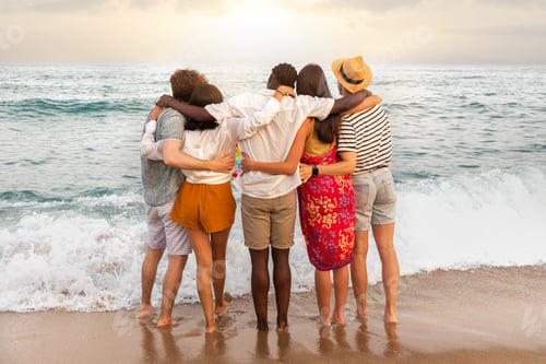 Preview: Rear view of multiracial friends embracing looking at the ocean relaxing during vacation trip.