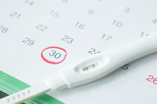 Preview: Pregnancy test kit on a calendar close up