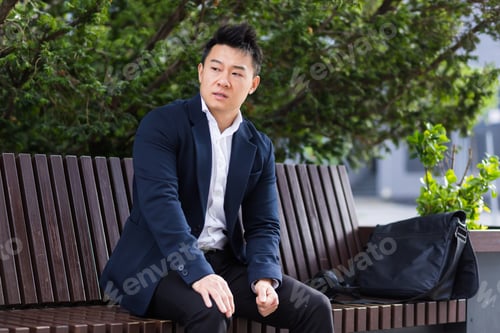 Preview: Asian businessman tired after work, sitting on a bench with fatigue and headache