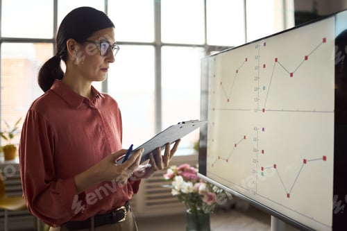 Preview: Caucasian Woman Analyzing Financial Charts on Digital Display