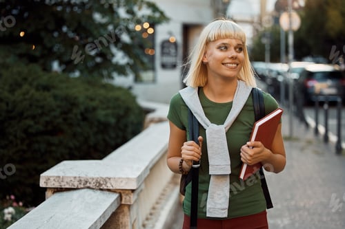 Preview: Happy female student walking through the city and looking away.