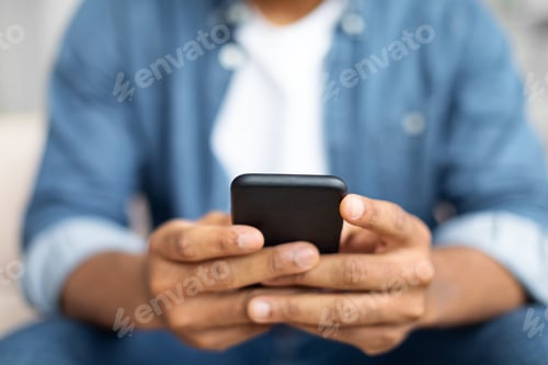 Preview: Black Man Sitting on Couch Using Cell Phone