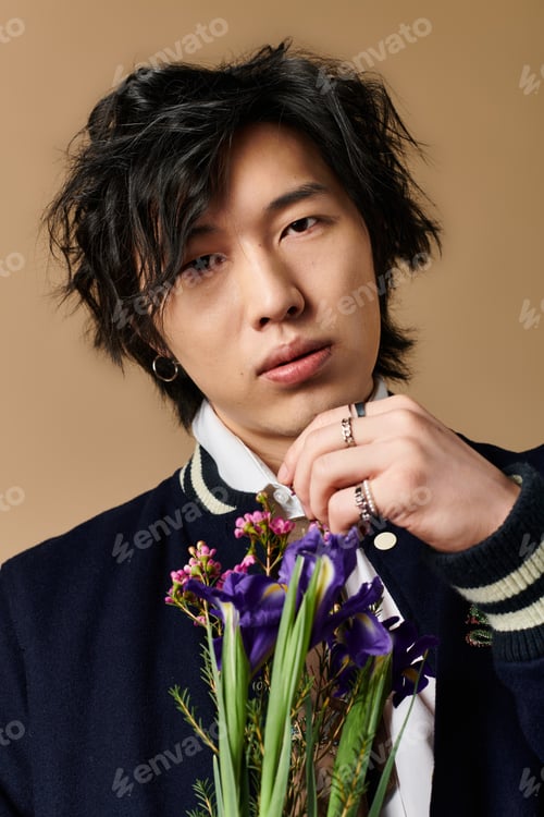 Preview: Stylish Asian man showcases spring fashion in vibrant studio setting with fresh flowers