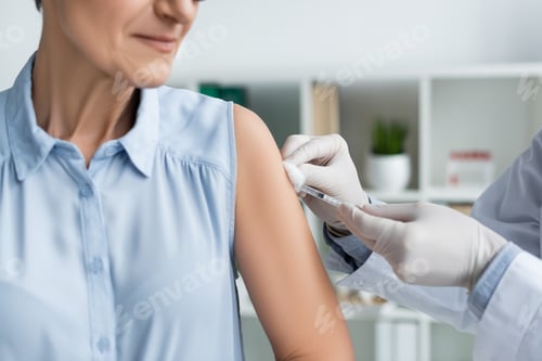 Preview: Cropped view of doctor doing vaccination of mature woman