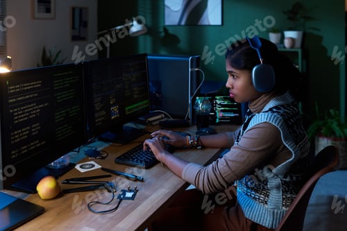 Preview: Young South Asian Woman Coding Software on Computer Monitors at Night
