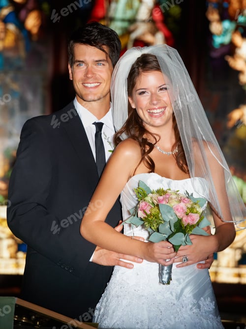 Preview: Newlywed bliss. Portrait of a happy newlywed couple standing in front of stained glass windows.