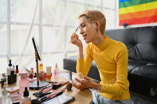 Preview: Smiling Asian gay man blogger filming daily makeup routine tutorial on smartphone.