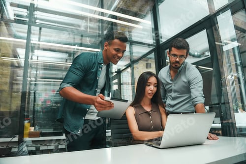 Preview: Successful team. Group of three young and cheerful employees using modern technologies and