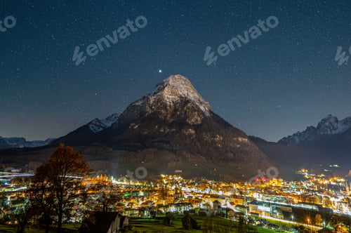 Preview: Beautiful view of the Swiss alps and Glarus city buildings covered with lights during night