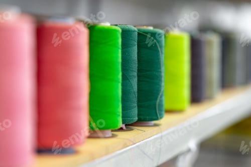 Preview: Row of multicolored thread spools at sewing factory