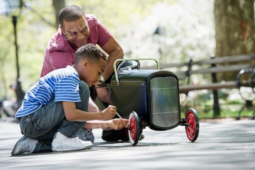 Preview: A family in the park on a sunny day. A boy repairing an old fashioned toy peddle car.