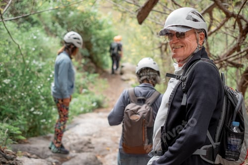 Preview: Happy senior friends hikers with backpacks enjoying trekking day on mountain, holidays concept