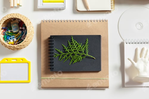 Preview: Leaf and notebook placed on a table with various stationery items arranged around them